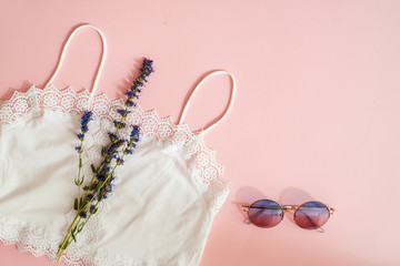 Top view flat lay.essential modern young lady or girl on vacations.Beach fashion , summer concept. Trendy colors.Fashion glasses, natural cotton openwork T-shirt, exotic leaves on a pink background