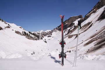 Pair of skis and ski poles in sharp focus with Avoriaz, Portes du Soleil, ski resort in the background in soft focus