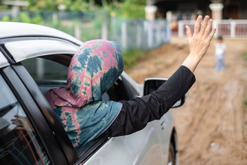 Young muslim woman waering hijab waving hand asking for help while her car stuck in mud. She...