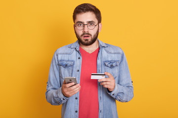 Close up portrait of man wearing casual red t shirt and denim jacket, making online shopping via...