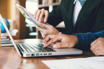 Business man hand holding graph chart and pointing graph chart for analyze the company's sales plan in the office.and partner examining market data on laptops.