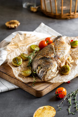 Grilled dorado with vegetables on a dark concrete background. Tasty sea fish. Fish Spar.