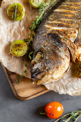 Fish Spar. Grilled dorado with vegetables on a dark concrete background. Tasty sea fish.