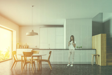 Woman in white and wooden kitchen with table