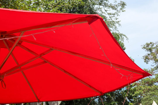 red umbrella hanging above or on the top as decoration with blue sky as background and green nature with beuatifull angle