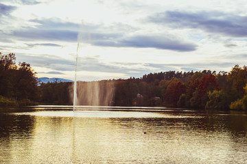 fountain spraying water against the background of autumn forest