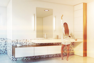Woman in white and mosaic bathroom with sink