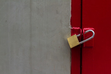 Close up textured of old dark cement wall and brass pad lock was locked the strong gate red slide door of restricted area background. Image for business secret or private zone with copy space.