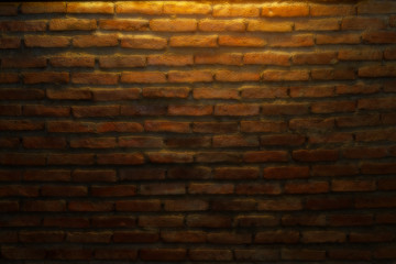Abstract background of beautiful empty dark brown brick blocks stone wall and warming light from an electric ceiling lamp in the coffee shop. Image taking from a soft focus lens filter.