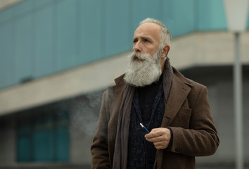 Elegant gentleman with long beard smoking outdoor.