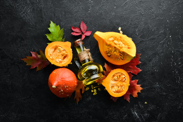 Pumpkin oil and pumpkins. Autumn vegetables. flat lay. On a black stone background. Top view. Free...