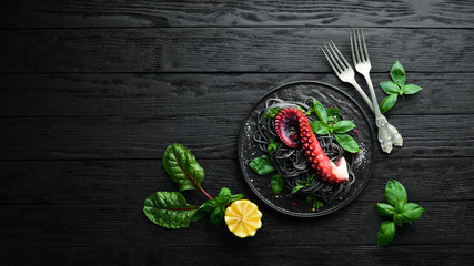 Black pasta with octopus tentacles. Seafood on a stone plate. In the old background. Top view. Free copy space.
