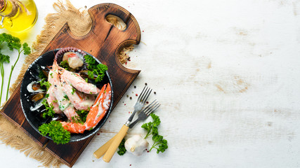 Boiled Seafood in a creamy sauce on a black stone plate. Seafood, prawns, shellfish, lobster. Top view. Free copy space.
