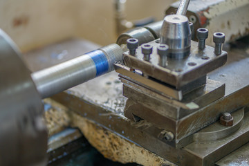 The lathe machine cutting the thread on the steel shaft.The turning machine making the thread on the steel shaft