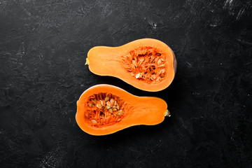 Fresh pumpkin, autumn vegetables. On a black stone background. Top view. Free copy space.