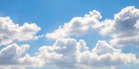 The white fluffy clouds and light blue sky in the sunny day. 