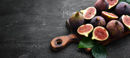 Fresh figs on black stone background. Tropical fruits. Top view. Free copy space.