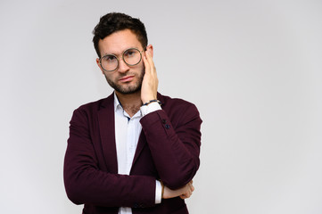 Men's fashion concept. Portrait of a handsome male model in glasses shows hands wearing a dark jacket, posing on a gray background. Black hair. Close Studio Shot