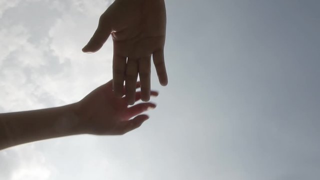 Successful team: many hands holding together on sky background in slowmotion
