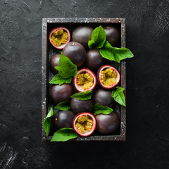 Fresh passion fruit with leaves in Wooden Box. Tropical Fruits. Top view. Free space for text.