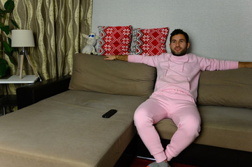 Young television addict man sitting on sofa at home and watching TV using remote control, looking excited, pumping out someone else's comedy comedy movie or live music at night