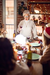 Beautiful group of women smiling happy and confident. On of them holding cup of wine speaking speech celebrating christmas at home