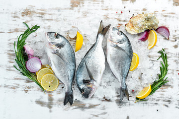 Raw fish with lemon and spices on a white background. Fish dorado. Top view. Free space for your...