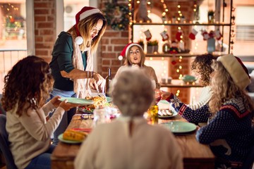 Beautiful group of women smiling happy and confident. Carving roasted turkey celebrating christmas at home