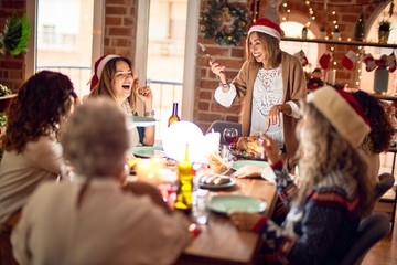 Beautiful group of women smiling happy and confident. Carving roasted turkey celebrating christmas at home