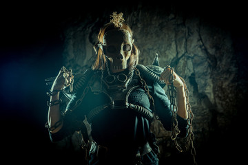 Post-apocalyptic woman in the rusty skull mask on the dungeon background. Nuclear post-apocalypse...