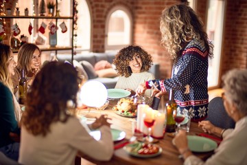 Beautiful group of women smiling happy and confident. Carving roasted turkey celebrating christmas at home