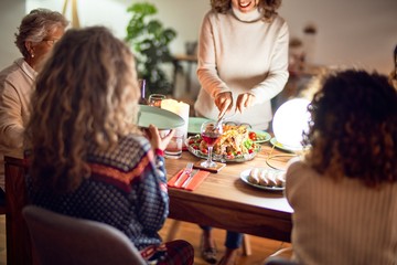 Beautiful group of women smiling happy and confident. Carving roasted turkey celebrating thankgiving day at home