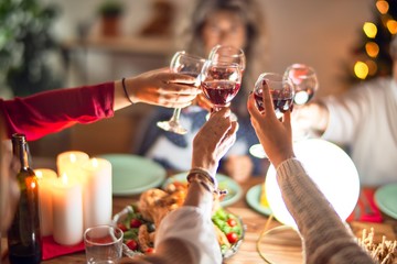 Beautiful group of women smiling happy and confident. Eating roasted turkey and toasting with cup...