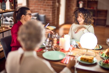 Beautiful group of women smiling happy and confident. Eating roasted turkey and serving wine on cup celebrating christmas at home