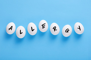 Fresh white farm eggs lined up in a row with the word allergy written on them