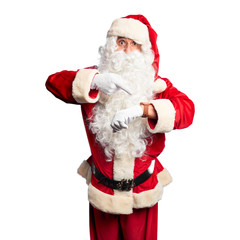 Middle age handsome man wearing Santa Claus costume and beard standing In hurry pointing to watch time, impatience, upset and angry for deadline delay