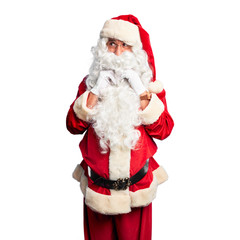 Middle age handsome man wearing Santa Claus costume and beard standing laughing nervous and excited with hands on chin looking to the side