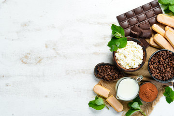 Ingredients for dessert tiramisu on a white wooden background.