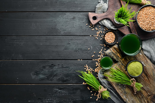 The juice from the green sprouted wheat, and wheat grains. On a black background. Micro Green. Healthy food. Top view. Free space for your text.