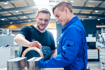 Master discussing a workpiece with his apprentice or trainee - 300103402
