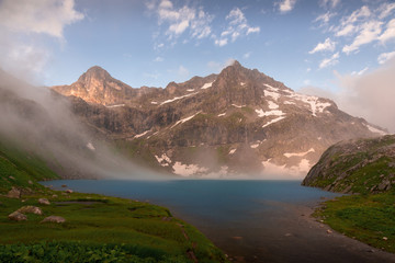 Alpine lake Kluhor on the border of Russia and Abkhazia, evening with clouds in the sky