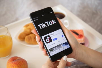 Woman holding iPhone 8 Plus with TikTok on the screen.