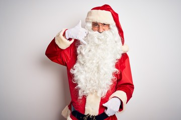 Middle age handsome man wearing Santa costume standing over isolated white background smiling doing phone gesture with hand and fingers like talking on the telephone. Communicating concepts.