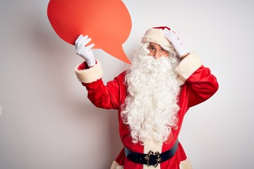 Middle age man wearing Santa costume holding speech bubble over isolated white background stressed with hand on head, shocked with shame and surprise face, angry and frustrated. Fear and upset
