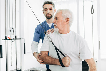 Senior patient training with his kinesiotherapist ,recovery with special exercises. Joint...