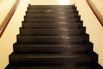 Dark brown stairs with reflection of yellow rays of artificial light