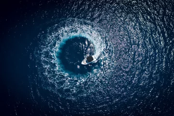 Keuken foto achterwand Nachtblauw Boot op zee maakt een cirkel in vogelperspectief