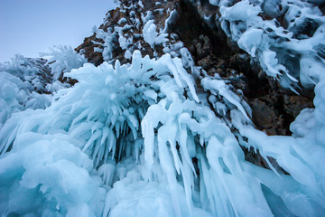 Very beautiful icicles hanging on a high rock. A lot of blue ice formed from the wind and frost.