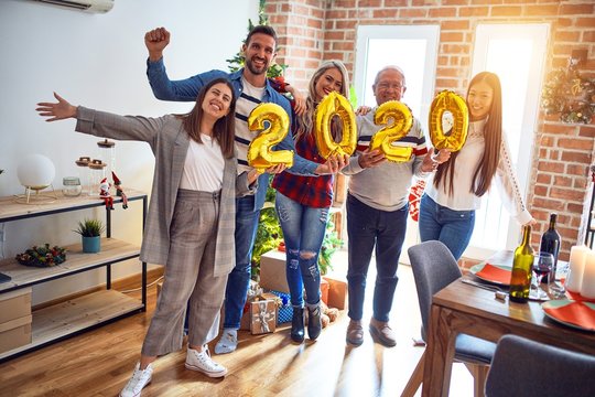 Beautiful family smiling happy and confident. Standing posing with tree holding balloons celebrating New Year at home