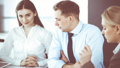 Group of business people discussing questions at meeting in modern office. Managers at negotiation or brainstorm. Teamwork, partnership and business concept